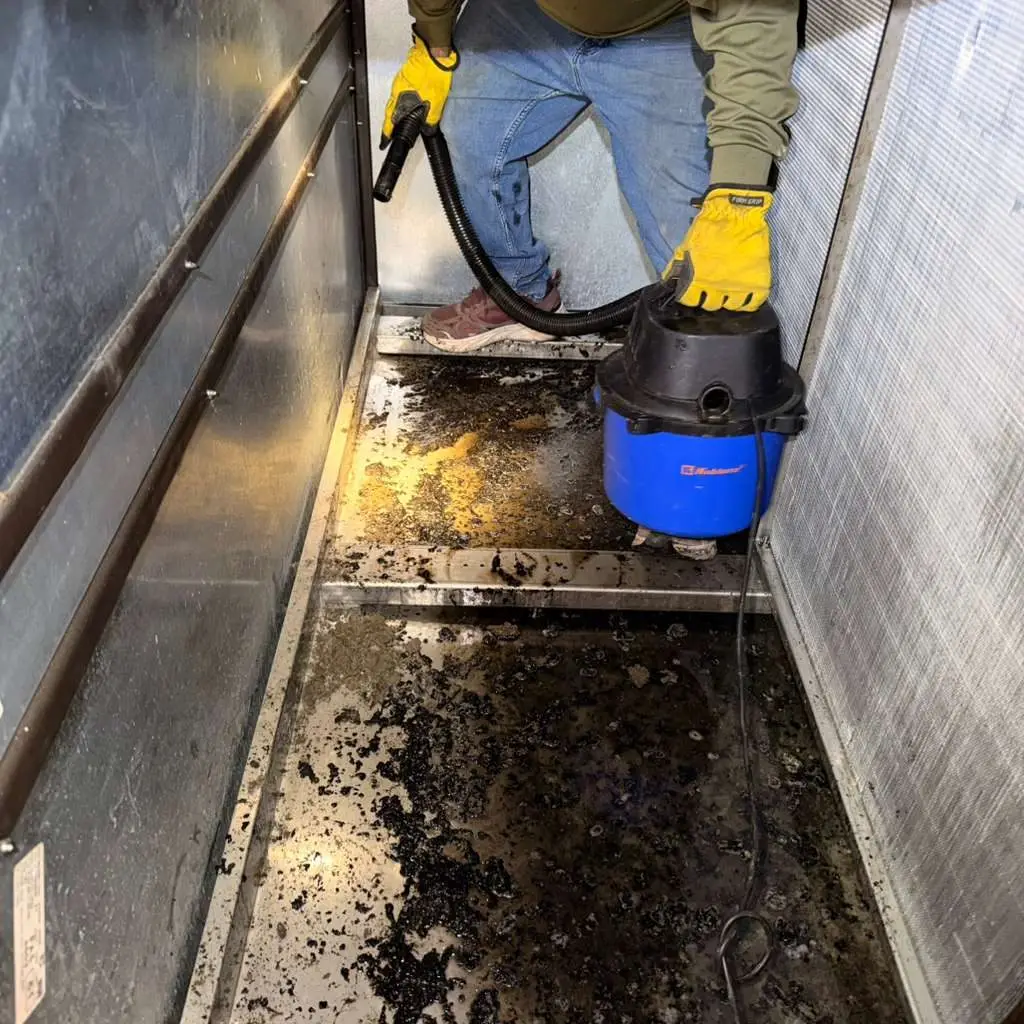 Extreme Air Duct technician vacuuming debris from a commercial air handler at the Katy Police Department