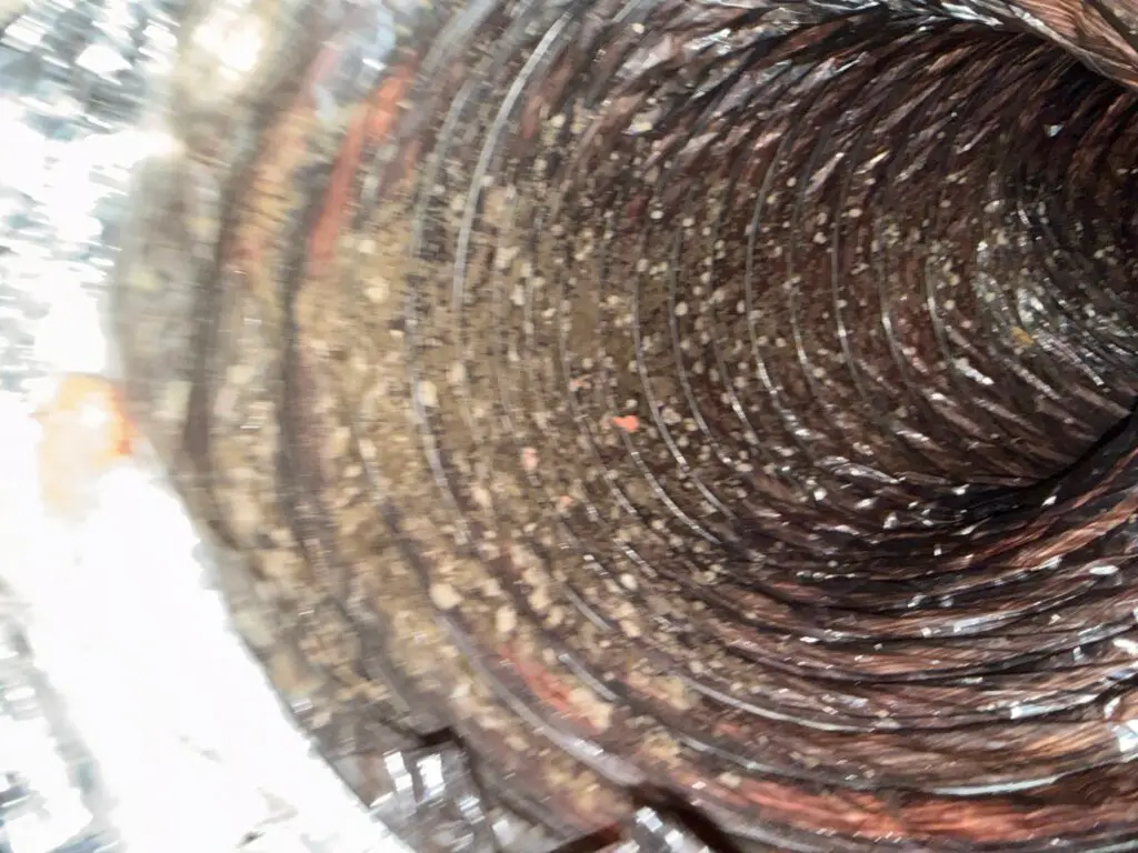 Dust and debris buildup inside a flex air duct before cleaning at a Houston area home