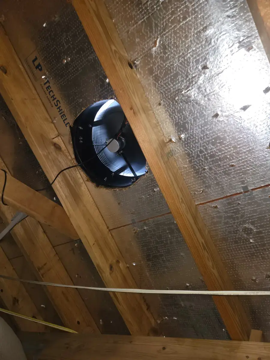 Solar attic fan mounted in the roof deck, seen from inside a Houston attic with radiant barrier decking