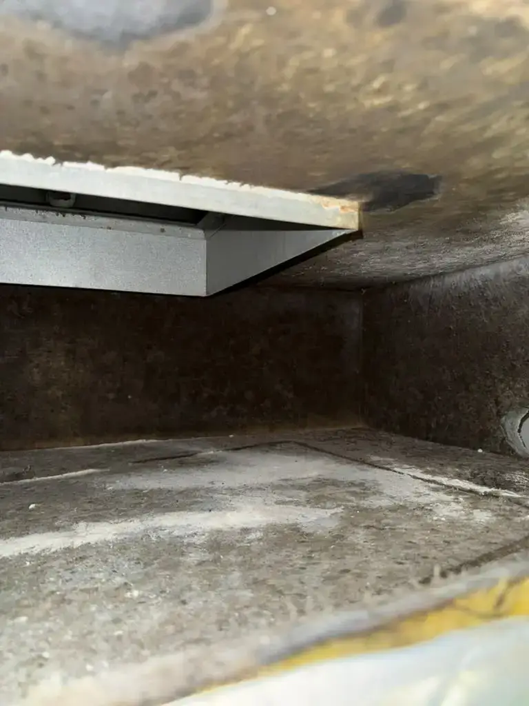Heavy dark buildup inside a return plenum before air duct cleaning in Katy, TX 77450