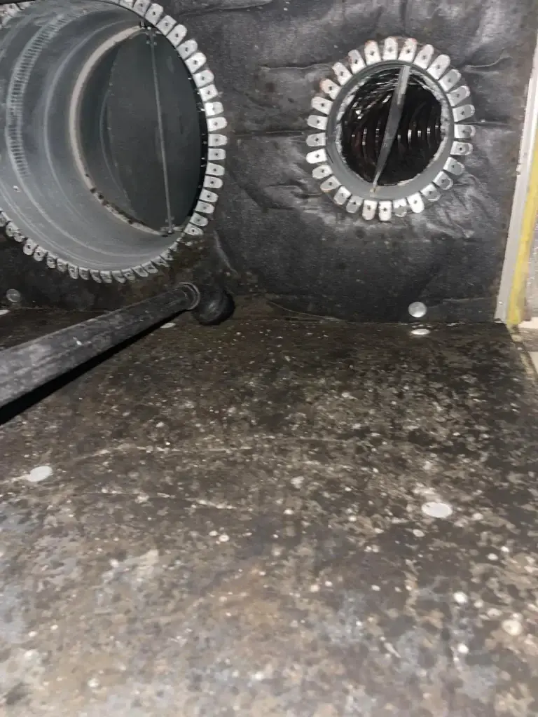 Buildup speckled across a supply plenum liner before duct cleaning in Bellaire, TX