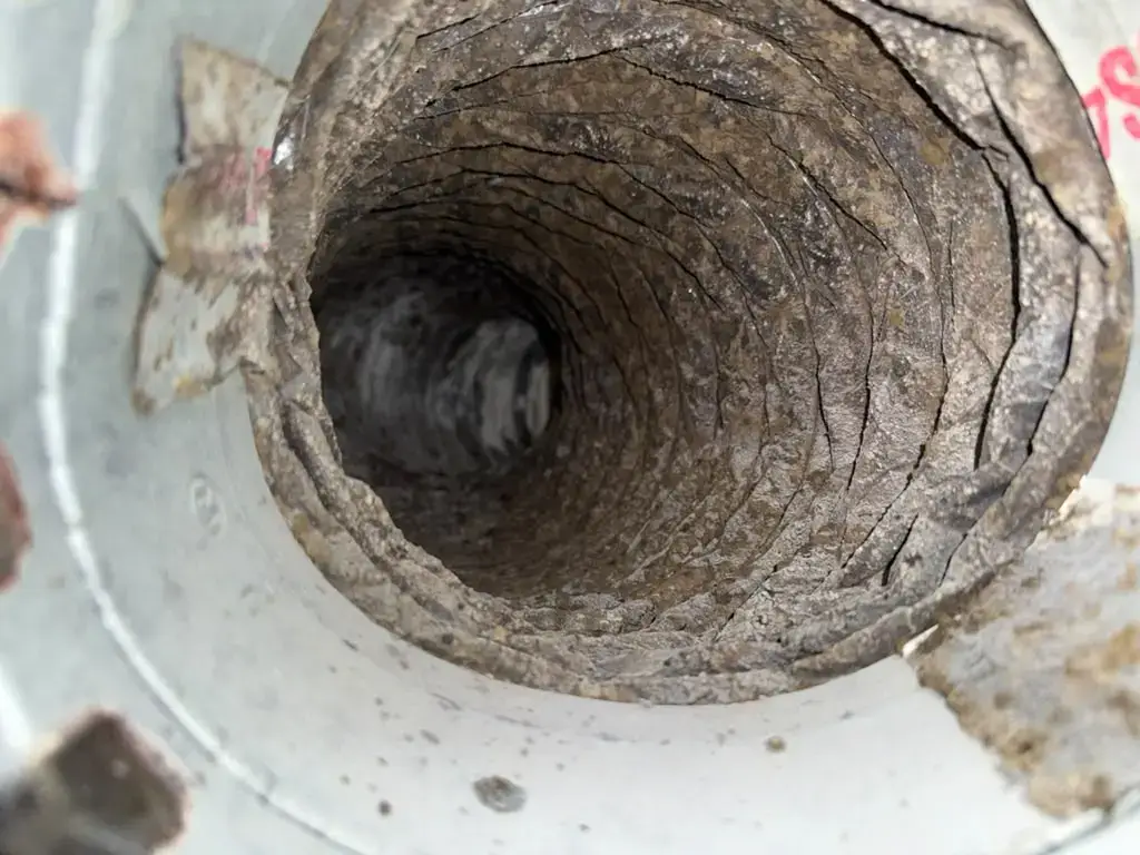 Flex duct interior lined with debris before cleaning at a Katy, TX home