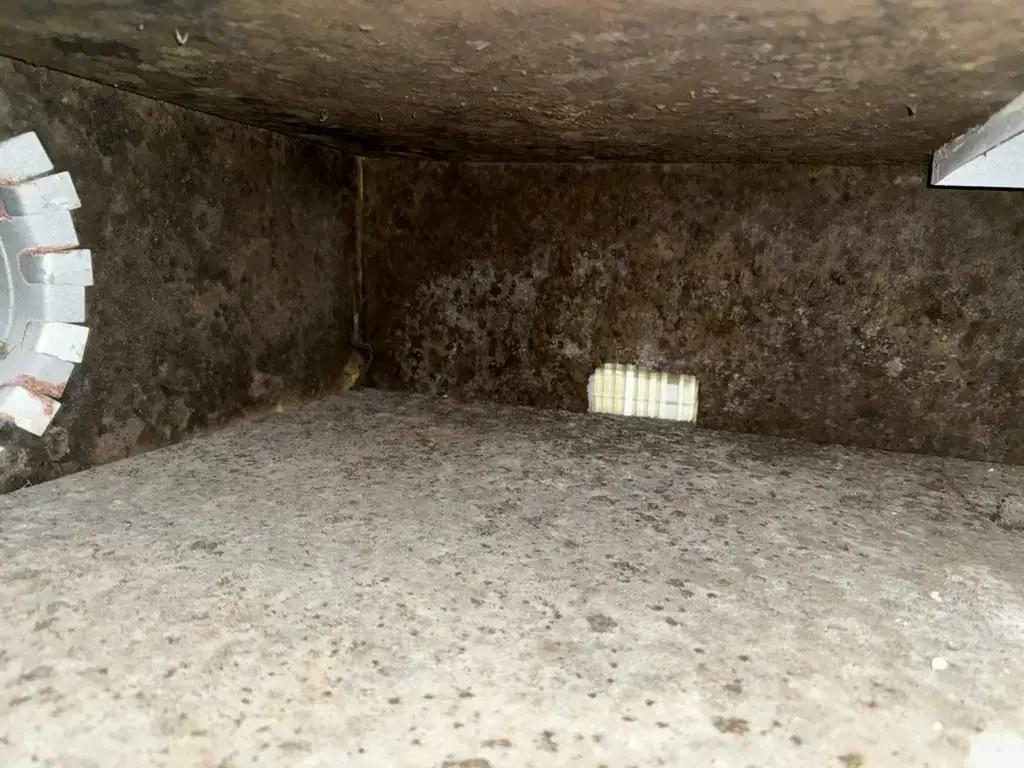 Duct board plenum walls coated with buildup before cleaning in Katy, TX