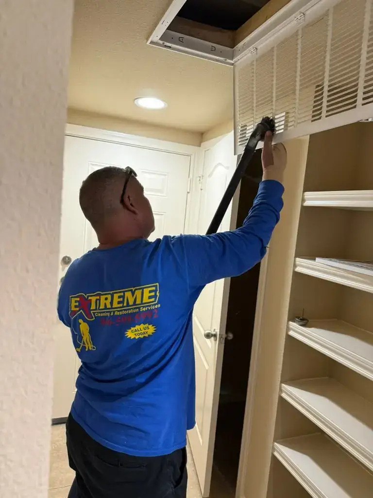 Extreme Air Duct technician brush-cleaning a return air grille in Katy, TX