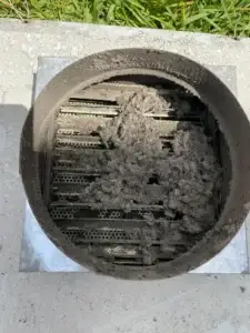 Rooftop exhaust termination cap heavily clogged with dust and debris before cleaning