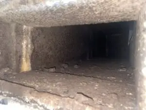 Heavy dust buildup inside a ductboard supply duct before air duct cleaning in Montrose, Houston 77006
