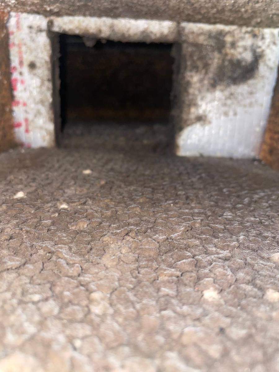 Close-up of thick dust buildup covering the inside of an apartment air duct in Montrose, Houston